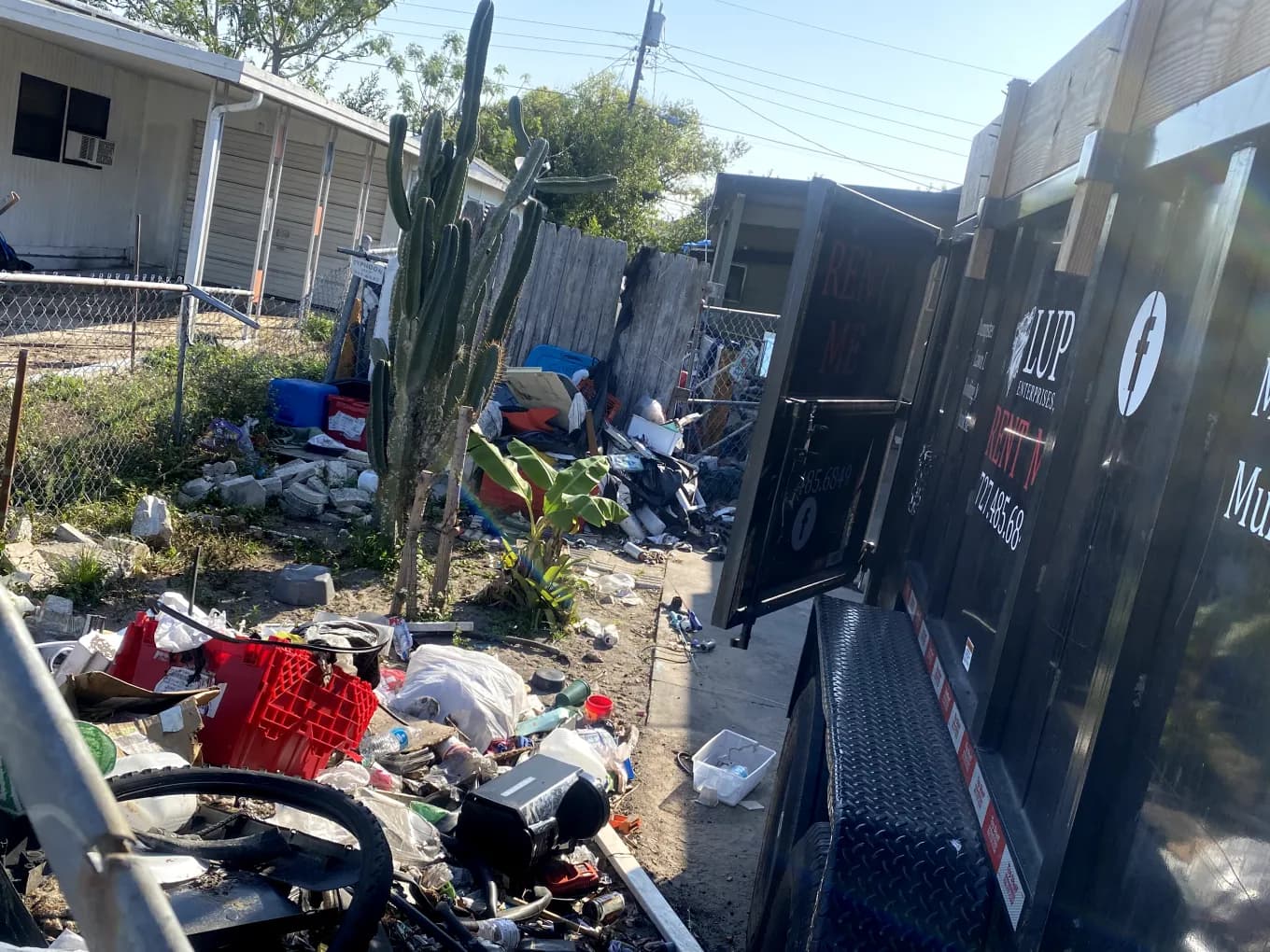Lupo dumpster trailer beside a cluttered yard during a home cleanout like the ones we do in Largo, FL