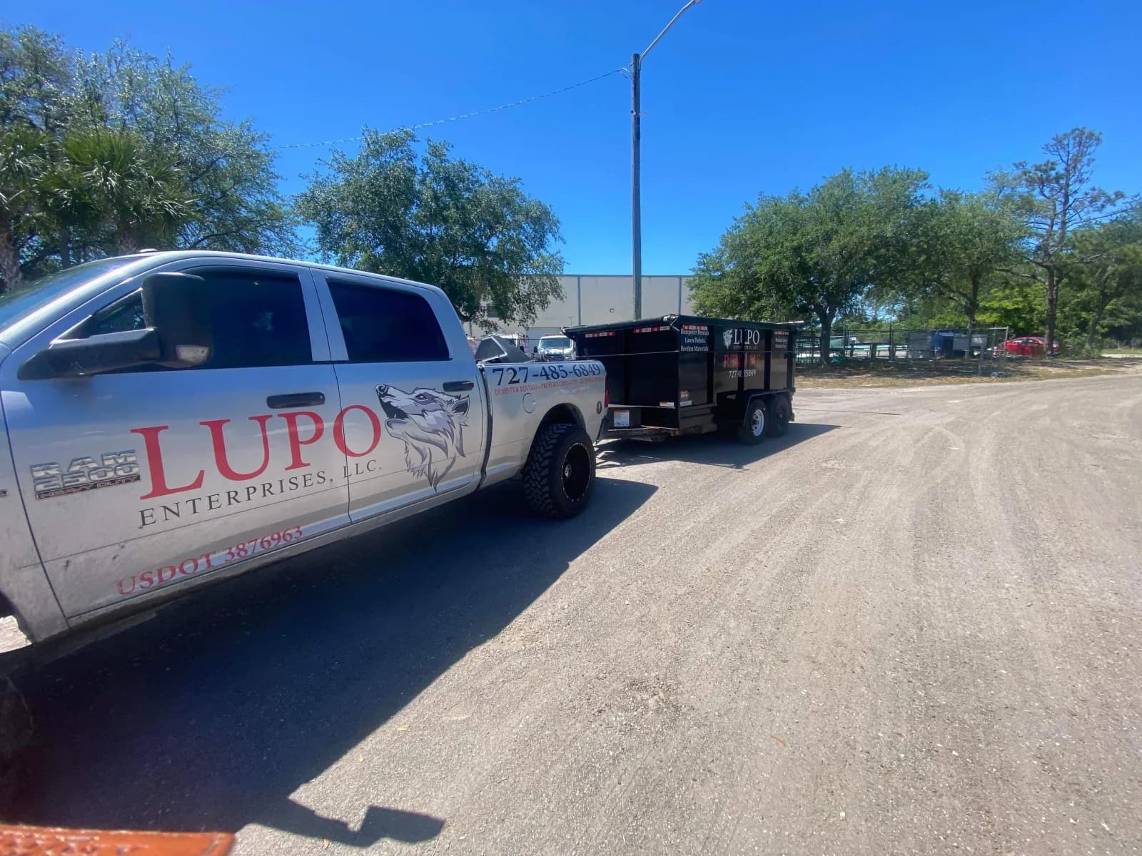 Lupo truck towing a low-profile dumpster trailer on the way to a St. Petersburg, FL job